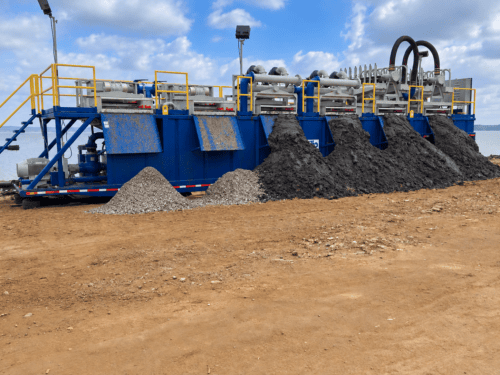 Triflo ES 2000R environmental dewatering system processing slurry, with separated solids discharged into piles beneath the screening units.