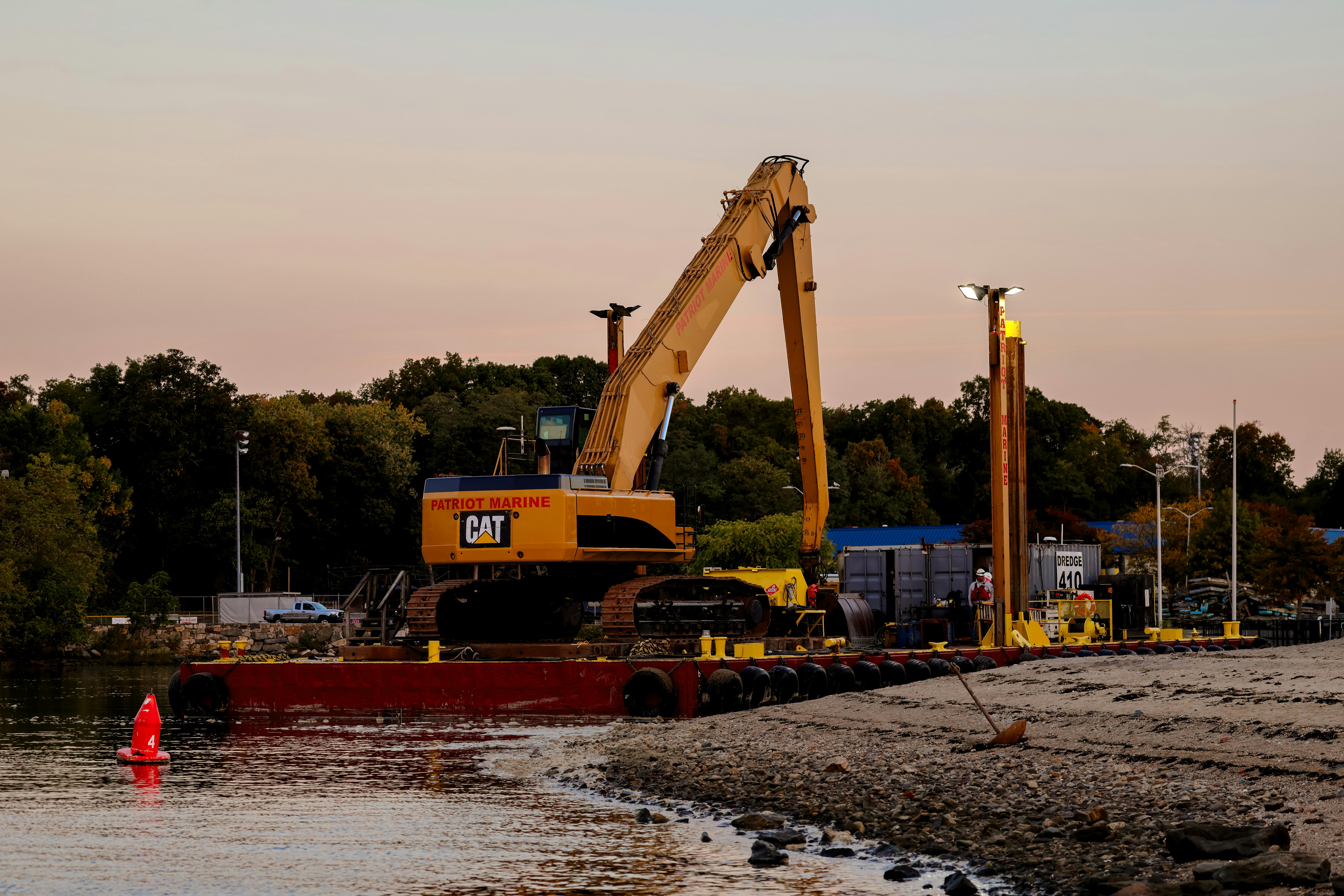 An excavator on a barge near Cove Island Park Marina during twilight in Stamford, Connecticut.